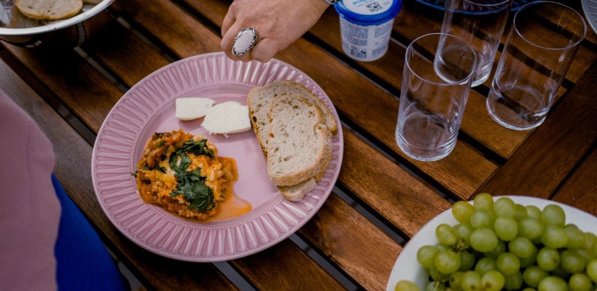 A casual outdoor dining table with bread, greens, and a side dish for brunch.