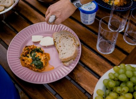 A casual outdoor dining table with bread, greens, and a side dish for brunch.